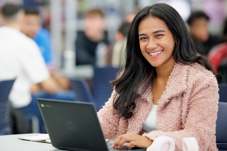 Smiling female student with laptop