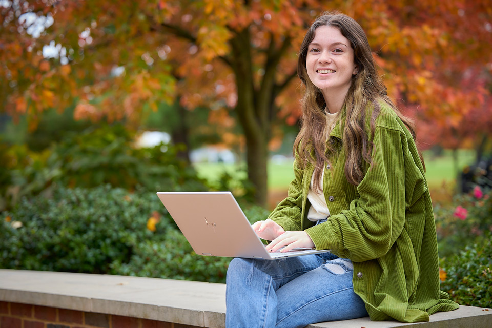 student sitting on wall smiling