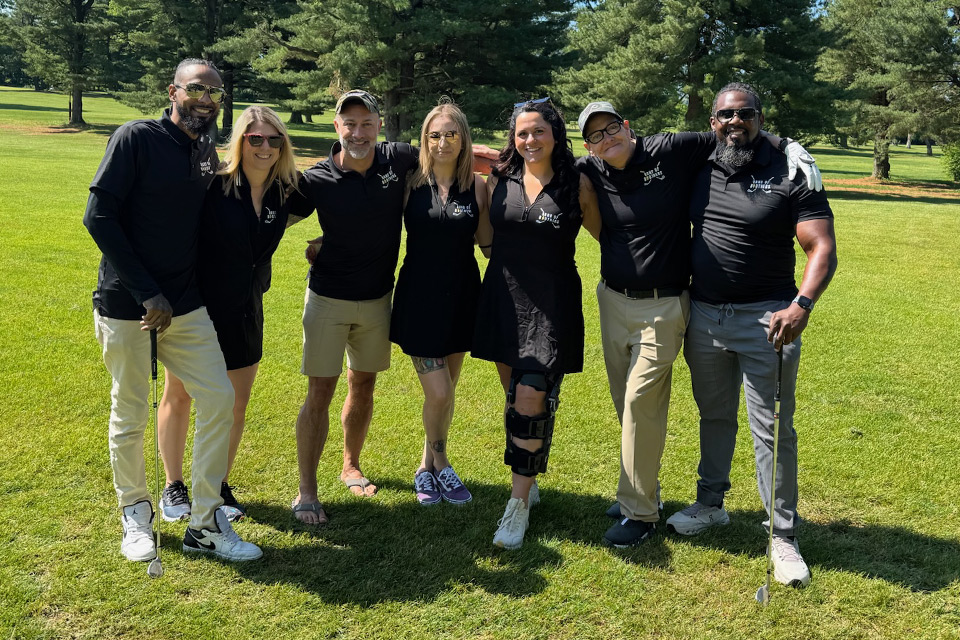 Diverse group of veterans posign for a picture on a golf course