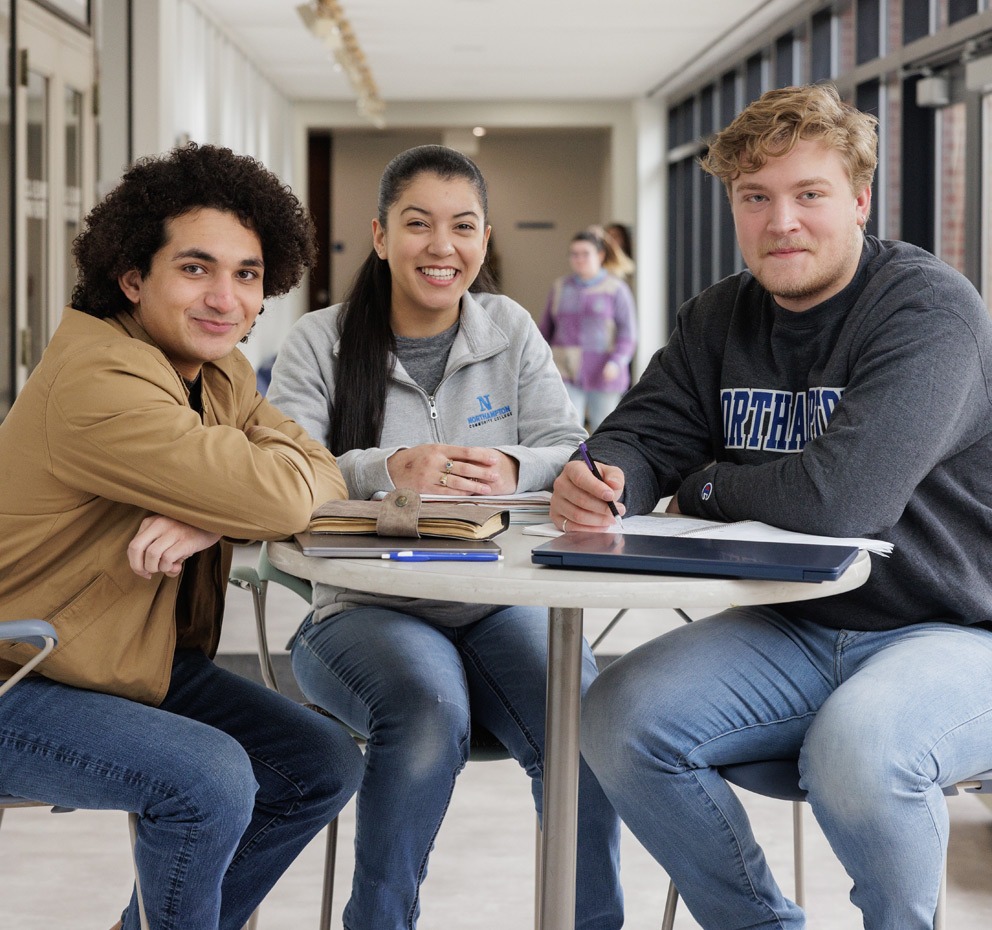 Three students stitting at a round table